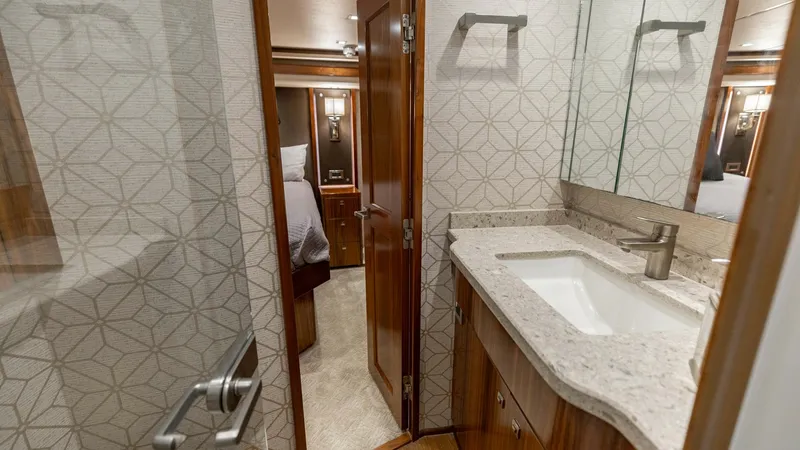 Slide: The Image of Luxurious Ensuite Bathroom This elegant ensuite bathroom on the 2018 Viking 72 Convertible features a sleek countertop with a modern sink and faucet. The stylish geometric wallpaper adds a touch of sophistication, complemented by the warm wood cabinetry. Ample mirror space enhances - 7460587
