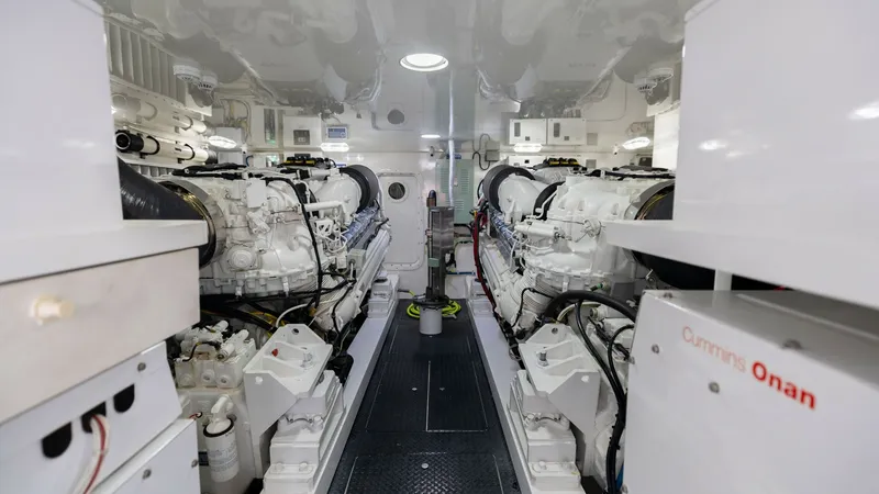 Slide: The Image of Spacious Engine Room with Twin Engines The engine room of the 2018 Viking 72 Convertible showcases a meticulously organized layout featuring dual diesel engines. The pristine white finish and ample lighting highlight the advanced engineering and accessibility for maintenance. A Cummins Onan ge - 7460599