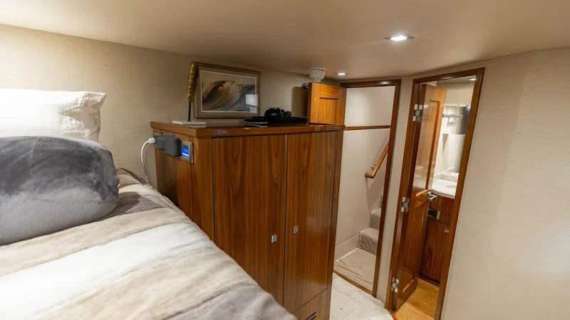 Slide: The Image of Guest Stateroom with En Suite Access This cozy guest stateroom on the 2018 Viking 72 Convertible features a plush bed with elegant bedding, providing a restful retreat. The warm wood cabinetry adds a touch of classic luxury, while the en suite bathroom access ensures privacy and convenience. - 7460594
