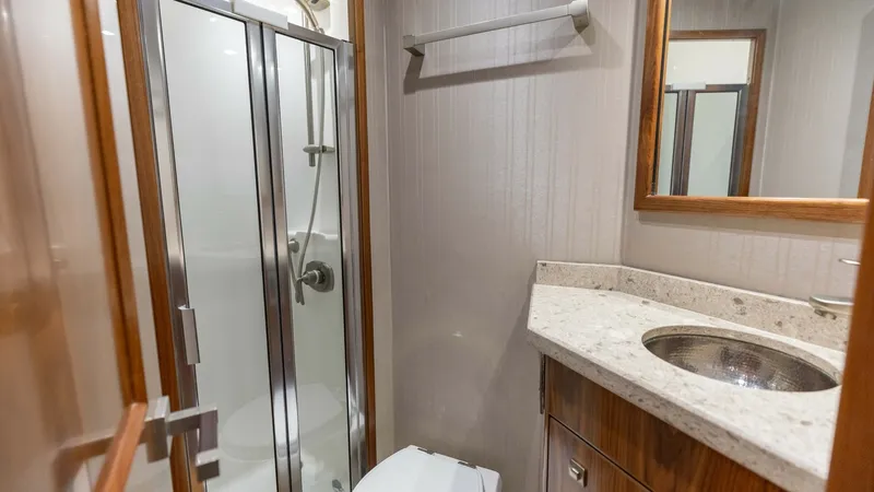 Slide: The Image of Elegant En-Suite Bathroom This luxurious en-suite bathroom on the 2018 Viking 72 Convertible showcases a sleek, modern design. The space features a glass-enclosed shower, elegant wood cabinetry, and a polished stone countertop with an undermount sink. Its efficient layout ensures - 7460593
