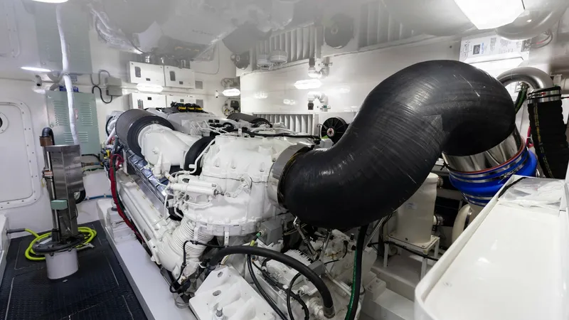 Slide: The Image of Engine Room with Twin Engines The engine room of the 2018 Viking 72 Convertible showcases a meticulously organized space featuring powerful twin engines. The pristine white interior is complemented by efficient lighting, ensuring easy access and maintenance. This area highlights advan - 7460601