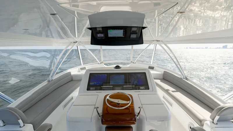 Slide: The Image of Flybridge Helm Station with Seating The flybridge helm station of this 2018 Viking 72 Convertible offers a commanding view, with state-of-the-art navigation displays integrated into a sleek console. The area features a polished wooden wheel and plush seating that wraps around the helm, prov - 7460612