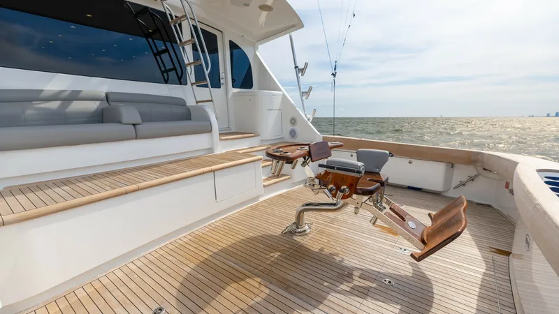 Slide: The Image of Spacious Aft Deck with Fighting Chair This image showcases the expansive aft deck of the 2018 Viking 72 Convertible, featuring a premium fighting chair ideal for fishing enthusiasts. The deck is elegantly finished with teak flooring and includes comfortable built-in seating for relaxation. Th - 7460605