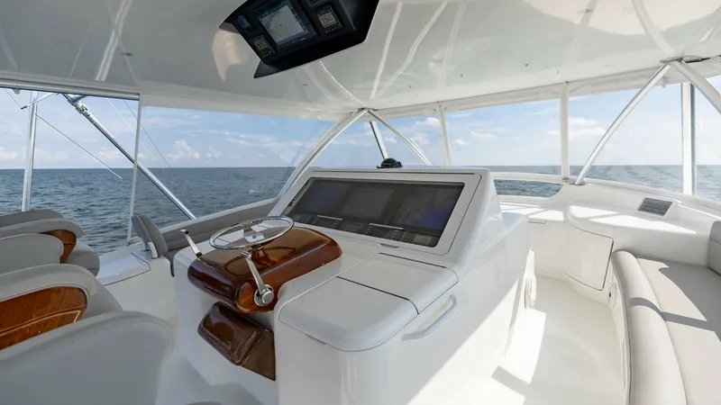 Slide: The Image of Flybridge Helm Station The flybridge helm station of the 2018 Viking 72 Convertible showcases a sleek, modern design with state-of-the-art navigation instruments. The ergonomic layout features a polished wood and stainless steel steering wheel, complemented by plush, comfortabl - 7460611