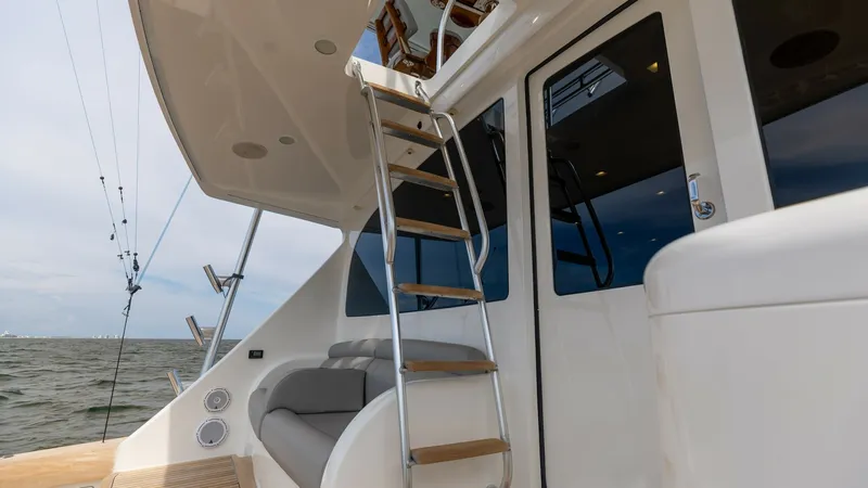 Slide: The Image of Flybridge Access Ladder and Aft Deck This image showcases the sleek access ladder leading to the flybridge of the 2018 Viking 72 Convertible. The aft deck is equipped with a comfortable seating area, perfect for relaxation while enjoying the open sea views. The polished stainless steel and t - 7460609