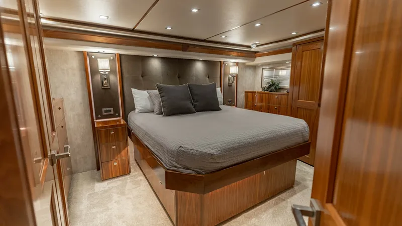 Slide: The Image of Luxurious Master Stateroom Interior The master stateroom of the 2018 Viking 72 Convertible exudes elegance and comfort with its rich wood finishes and plush carpeting. The centerpiece is a spacious, elevated bed surrounded by soft ambient lighting that creates a warm and inviting atmosphere - 7460583