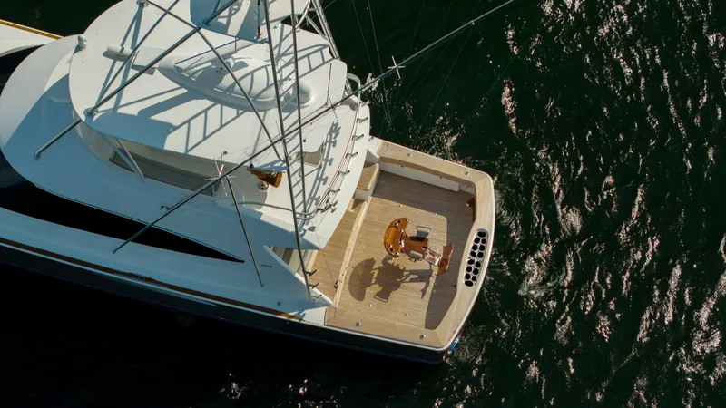 Slide: The Image of Aerial View of Aft Deck This image showcases the spacious aft deck of the 2018 Viking 72 Convertible. The deck features a clean, open layout ideal for fishing or relaxing, with high-quality teak flooring and a centrally positioned fighting chair. The surrounding rail and rod hol - 7460623