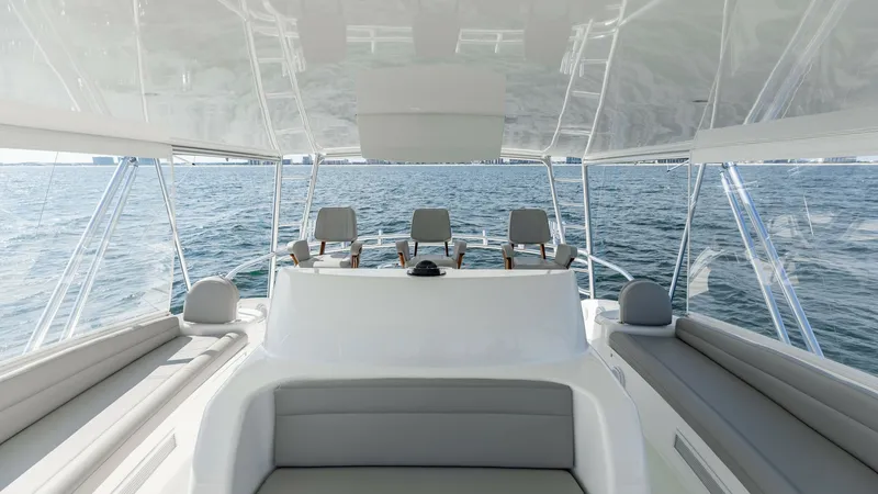 Slide: The Image of Flybridge Seating and Helm View This image showcases the spacious flybridge of the 2018 Viking 72 Convertible, featuring a sleek helm station with three comfortable captain's chairs. The seating area provides ample space for relaxation, with cushioned benches offering panoramic ocean vi - 7460617