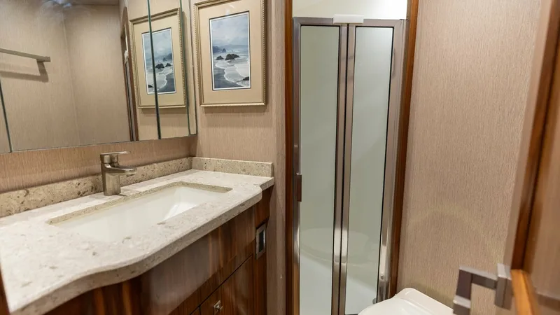 Slide: The Image of Luxurious Guest Bathroom This elegant guest bathroom on the Viking 72 Convertible features a spacious shower with glass doors, a sleek vanity with a polished stone countertop, and high-quality wood finishes. The tasteful artwork and ample mirror create a welcoming ambiance, while - 7460590