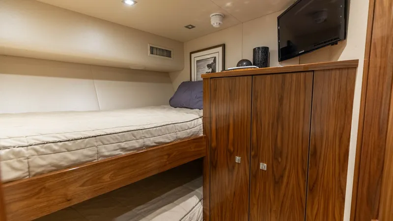 Slide: The Image of Guest Stateroom with Twin Bunks This cozy guest stateroom features twin bunk beds, providing comfortable accommodations for overnight stays. The warm wood cabinetry offers ample storage, complemented by soft ambient lighting. A built-in flat-screen TV adds a touch of modern convenience, - 7460591