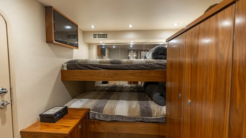 Slide: The Image of Guest Stateroom with Bunk Beds This inviting guest stateroom on the 2018 Viking 72 Convertible features comfortable bunk beds, perfect for accommodating additional guests. The warm wood finishes and soft ambient lighting create a cozy and welcoming atmosphere. Ample storage is availabl - 7460596