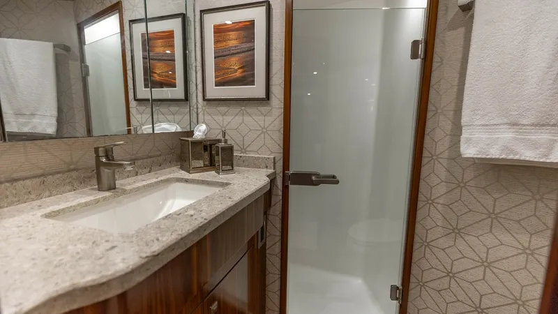 Slide: The Image of Luxurious Ensuite Bathroom This elegant ensuite bathroom on the 2018 Viking 72 Convertible features a sleek glass-enclosed shower and a stylish vanity with a polished stone countertop. The rich wooden cabinetry complements the modern fixtures, providing ample storage and a refined - 7460586