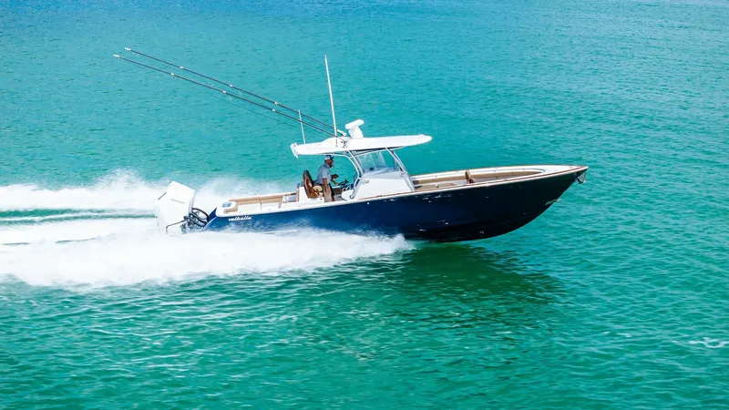 Slide: The Image of Side View of Valhalla V-37 in Motion The 2024 Valhalla V-37 'BIRD' is captured slicing through clear waters, showcasing its sleek hull and powerful outboard engines. The elegant design features a spacious center console with ample seating, ideal for both leisure and sport fishing. The stream - 7471241