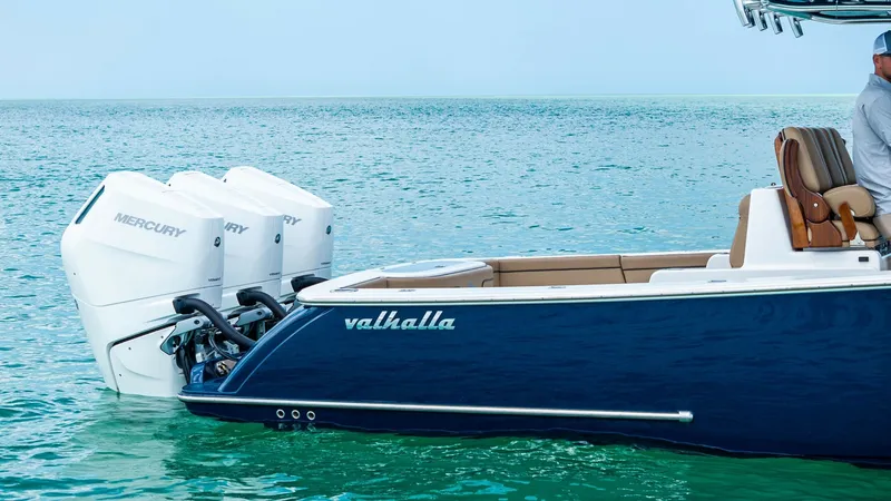 Slide: The Image of Aft View with Triple Outboards The aft section of the 2024 Valhalla V-37 showcases its powerful triple Mercury outboard engines, offering exceptional performance and speed. The sleek, deep blue hull complements the elegant design, while the spacious aft seating provides comfort and sty - 7471237