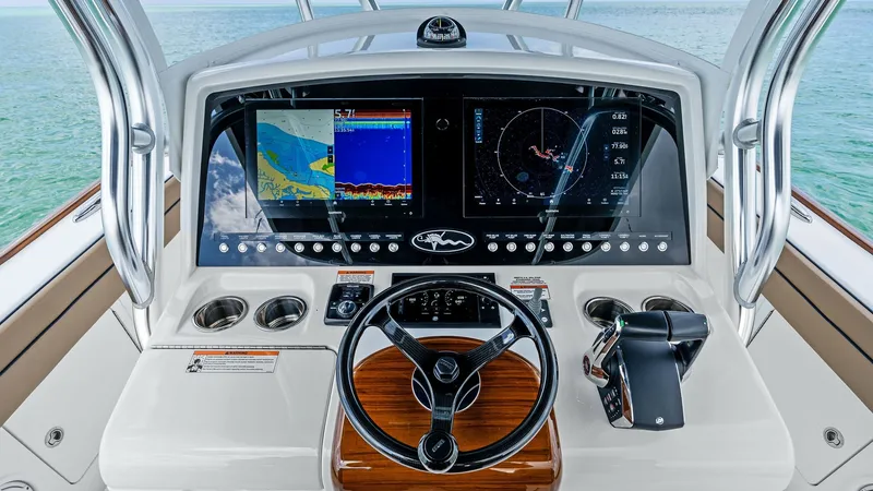 Slide: The Image of Helm Station with Navigation Screens The helm station of the 2024 Valhalla Boatworks V-37 'BIRD' features state-of-the-art navigation technology, including dual multifunction displays. The sleek design is complemented by a polished wood steering wheel and ergonomic controls, ensuring a comfo - 7471210