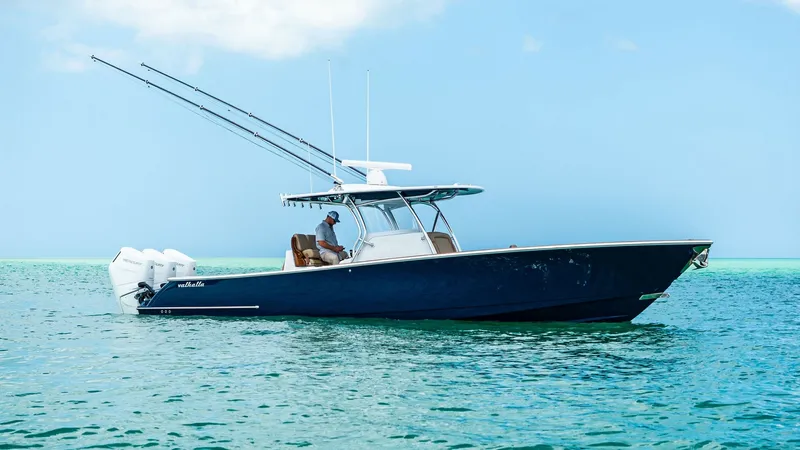 Slide: The Image of Side Profile of V-37 at Sea The 2024 Valhalla Boatworks V-37, named 'BIRD', is elegantly showcased in this side profile view. The sleek, deep blue hull cuts gracefully through the water, complemented by the vessel's powerful twin outboard engines. The T-top provides shade and style, - 7471235