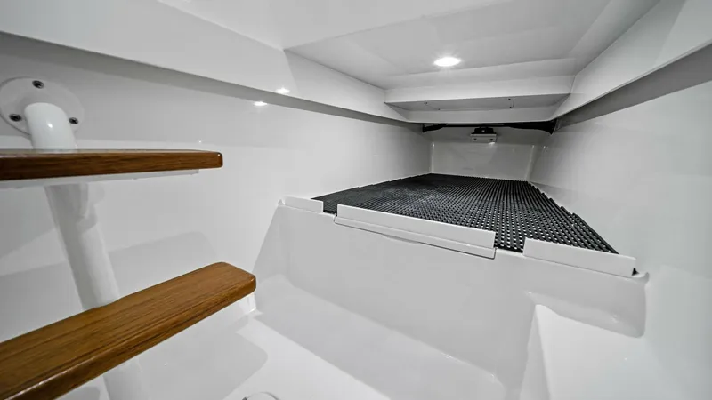 Slide: The Image of Forward Cabin with Storage Area This image showcases the forward cabin of the 2024 Valhalla Boatworks V-37. The area features a sleek, white interior with practical storage options, highlighted by a textured mat for securing items. The wooden steps add a touch of elegance, leading to a - 7471183