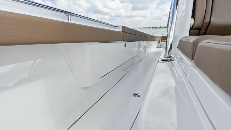 Slide: The Image of Starboard Walkway with Seating The starboard walkway of the 2024 Valhalla Boatworks V-37 features sleek white finishes, providing a modern aesthetic. Comfortable tan cushions line the seating area, offering both style and comfort for passengers. The clean lines and polished surfaces en - 7471191