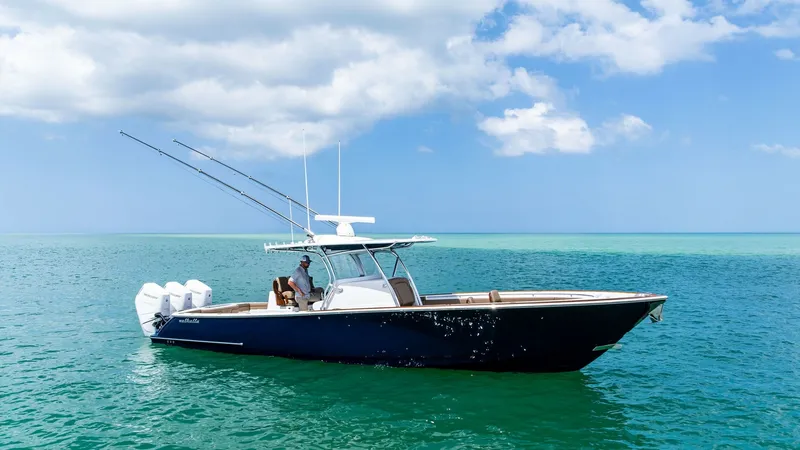Slide: The Image of Side Profile of Valhalla V-37 This image showcases the sleek side profile of the 2024 Valhalla V-37 from Valhalla Boatworks. The vessel is elegantly poised on clear blue waters, highlighting its modern hull design and powerful triple outboard engines. The open deck layout is perfect f - 7471232