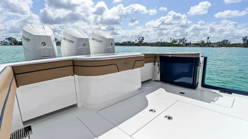 Slide: The Image of Spacious Aft Deck with Engines This image showcases the expansive aft deck of the 2024 Valhalla Boatworks V-37. The deck features sleek, modern flooring and ample seating with elegant upholstery, ideal for socializing or relaxing. Highlighted in the background are the powerful Mercury - 7471176