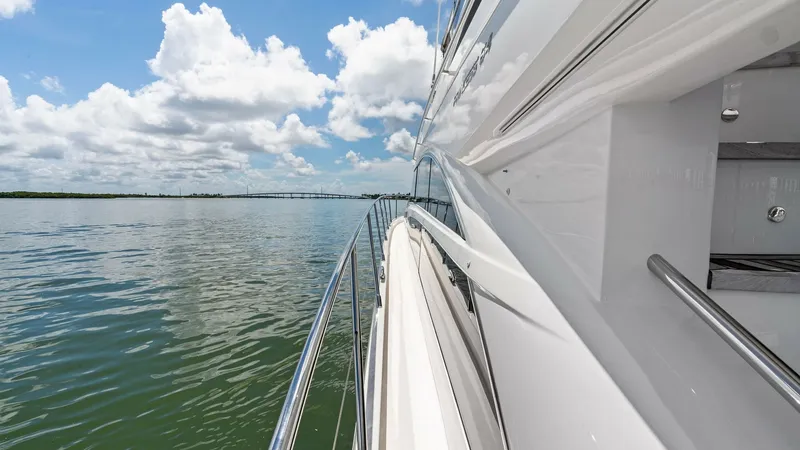 Slide: The Image of Starboard Side Deck with Railings This image captures the sleek, polished starboard side deck of the 2016 Princess 64 Flybridge, featuring sturdy stainless steel railings for safety and style. The smooth, glossy finish of the hull complements the expansive water views, creating a seamless - 7460862