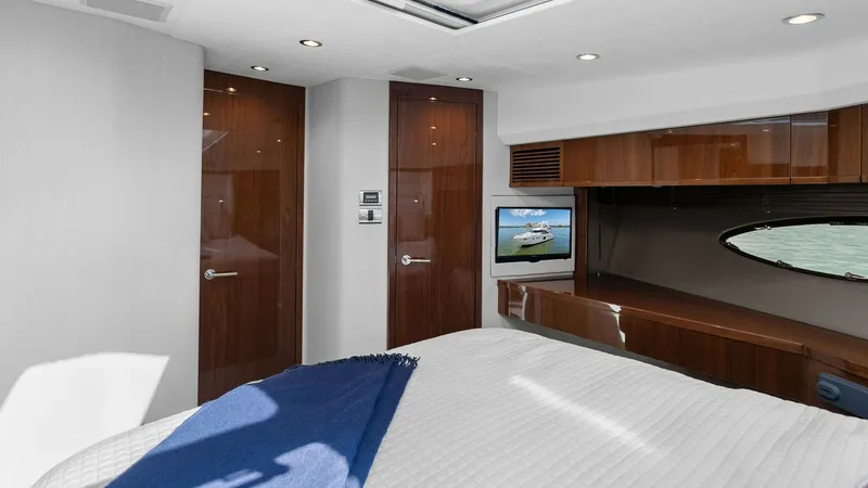 Slide: The Image of Luxurious Master Stateroom The master stateroom of the 2016 Princess 64 Flybridge exudes sophistication with its high-gloss wood finishes and plush bedding. A large oval window provides natural light and stunning views, complemented by modern recessed lighting. This space combines - 7460836