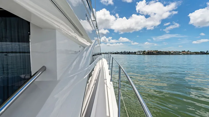 Slide: The Image of Starboard Side Deck View The starboard side deck of the Princess 64 Flybridge offers a sleek and polished walkway with stainless steel railings for safety. The glossy exterior finish reflects the serene water and sky, highlighting the yacht's elegant design. This side deck provid - 7460861