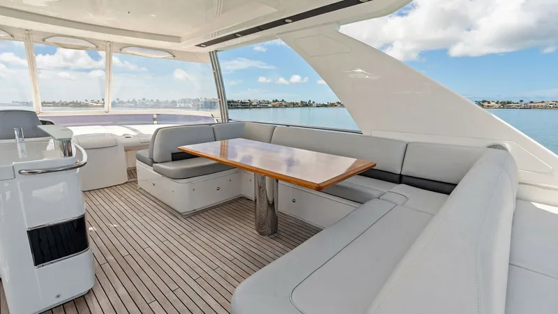 Slide: The Image of Flybridge Seating Area with Table This spacious flybridge on the 2016 Princess 64 features an expansive seating area with plush, cushioned benches surrounding a polished wooden table, perfect for alfresco dining. The teak decking and open design offer a luxurious and inviting atmosphere, - 7460852