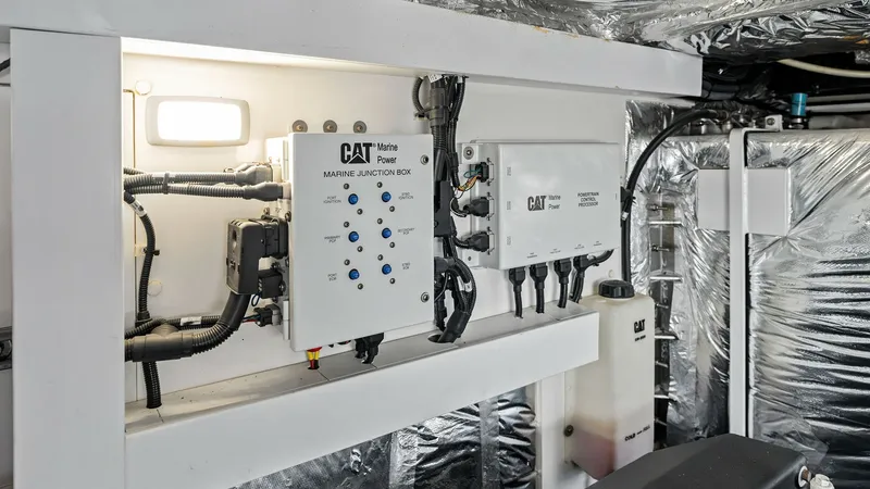 Slide: The Image of Engine Room Electrical Systems This image showcases the neatly organized electrical systems within the engine room of the 2016 Princess 64 Flybridge. The space features well-labeled CAT Marine Power junction boxes and a tidy arrangement of cables, reflecting meticulous design and atten - 7460886