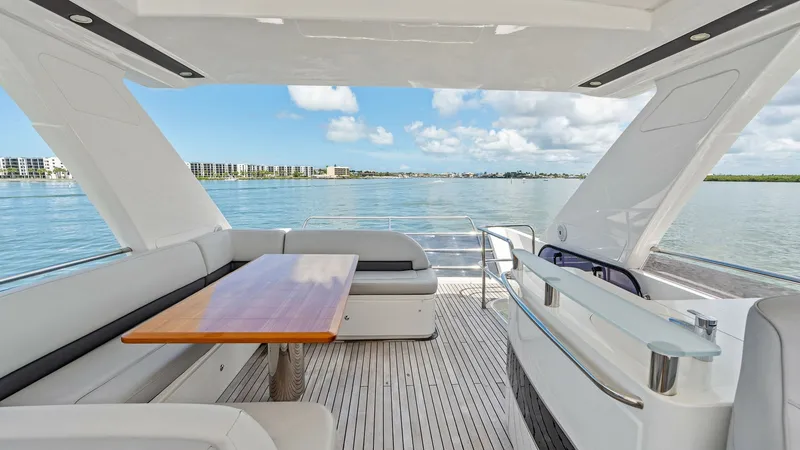 Slide: The Image of Spacious Flybridge Seating Area The flybridge of the 2016 Princess 64 offers a luxurious seating area with plush white cushions and a sleek wooden table, ideal for alfresco dining. The open layout provides panoramic views, enhancing the outdoor experience. Overhead, a stylish hardtop of - 7460859