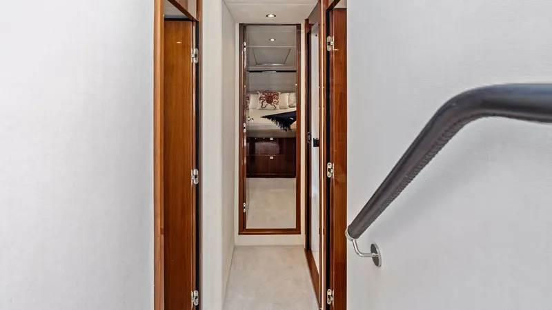 Slide: The Image of Elegant Cabin Corridor View This image showcases the sleek corridor leading to the staterooms on the Princess 64 Flybridge. Rich wooden finishes and soft lighting create an inviting atmosphere, complemented by the modern handrail design. The corridor's layout ensures easy access to - 7460833