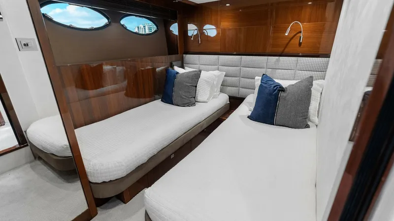 Slide: The Image of Twin Guest Cabin with Portholes This inviting twin guest cabin on the 2016 Princess 64 Flybridge features two comfortable single beds, accented with plush cushions. The space is elegantly finished with rich wood paneling and soft, neutral carpeting. Natural light flows through the styli - 7460843