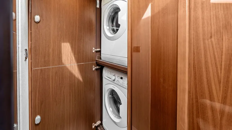 Slide: The Image of Laundry Cabinet with Washer and Dryer This image showcases the convenient laundry cabinet on the 2016 Princess 64 Flybridge, featuring a stacked washer and dryer. The elegant wood paneling complements the yacht's luxurious interior, providing both functionality and style. This essential ameni - 7460832