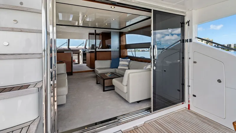 Slide: The Image of Salon Entrance from Aft Deck This image showcases the inviting entrance to the salon from the aft deck of the 2016 Princess 64 Flybridge. The sliding glass doors open to reveal a luxurious interior with plush seating, rich wood finishes, and ample natural light. The design seamlessly - 7460809