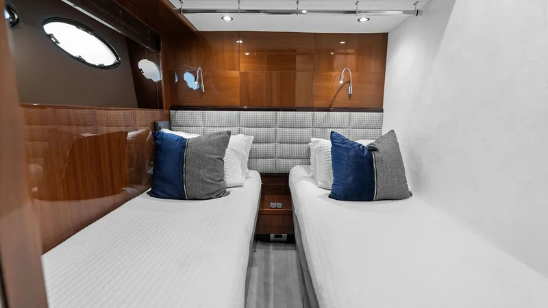 Slide: The Image of Twin Guest Cabin Interior View This elegant twin guest cabin features two neatly arranged beds with plush bedding, perfect for comfort and relaxation. The warm wooden paneling and modern reading lights add a touch of sophistication, while the soft grey upholstered headboard complements - 7460844