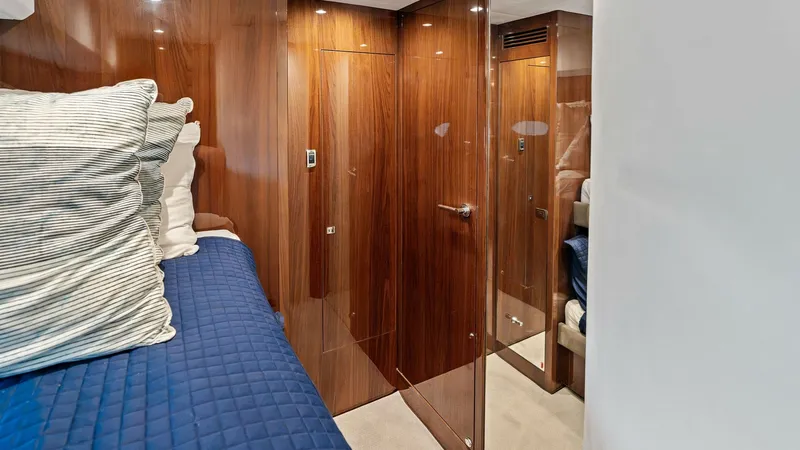 Slide: The Image of Guest Cabin with Ensuite Access This elegant guest cabin on the Princess 64 Flybridge features rich wood paneling and plush bedding, offering a luxurious retreat for guests. The room is thoughtfully designed with direct ensuite access, ensuring privacy and convenience. Soft ambient ligh - 7460847