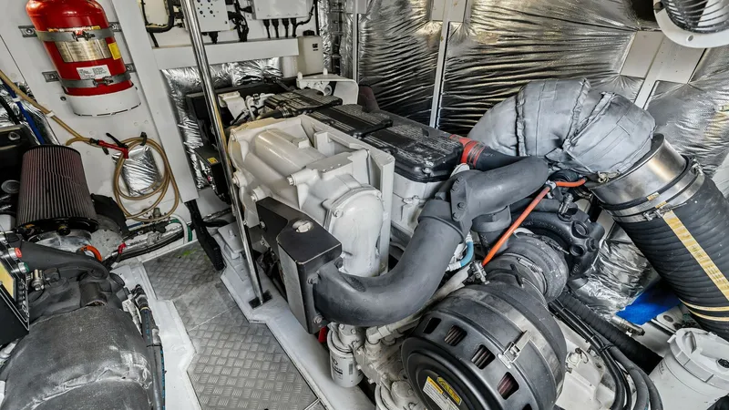 Slide: The Image of Engine Room with Twin CAT C18 ACERT Engines This image showcases the well-organized engine room of the 2016 Princess 64 Flybridge, featuring powerful and expertly maintained machinery. The space is equipped with modern insulation and secure wiring, ensuring optimal performance and safety. Notable e - 7460884