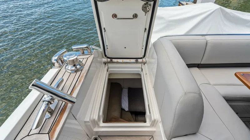 Slide: The Image of Flybridge Storage Compartment Access This image showcases the practical storage compartment located on the flybridge of the 2016 Princess 64 Flybridge yacht. The compartment is seamlessly integrated into the seating area, featuring a sturdy lid and easy access. The surrounding teak decking a - 7460870