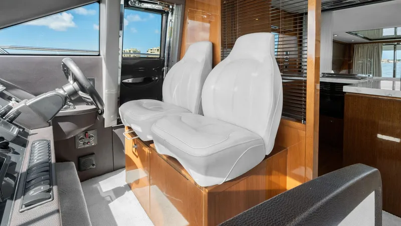 Slide: The Image of Helm Station with Dual Seating The helm station of the 2016 Princess 64 Flybridge features sleek dual seating with plush white leather upholstery, offering comfort and style. The expansive windows provide excellent visibility, complemented by a modern console with intuitive controls. R - 7460817