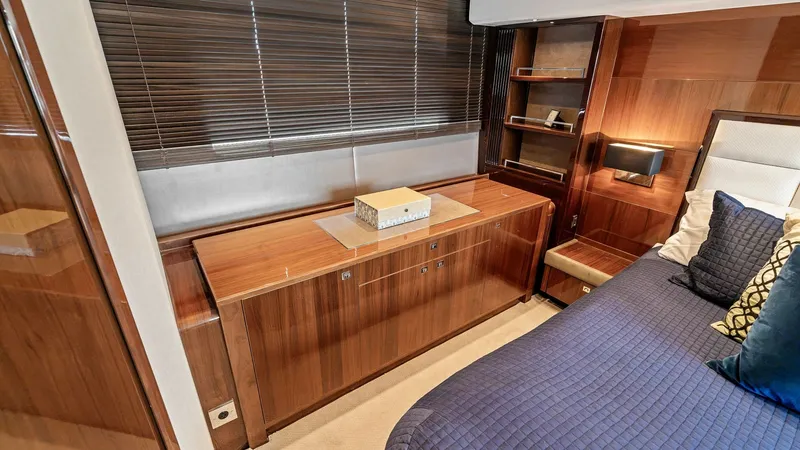 Slide: The Image of Master Stateroom with Luxurious Finishes This elegant master stateroom on the 2016 Princess 64 Flybridge features rich wood cabinetry and plush bedding, creating a warm and inviting atmosphere. The sleek built-in storage and shelving provide ample space, while the ambient lighting enhances the r - 7460825