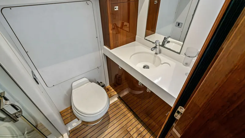 Slide: The Image of Crew Bathroom with Vanity This well-appointed guest bathroom on the 2016 Princess 64 Flybridge features a sleek vanity with an integrated sink and modern fixtures. The space is enhanced by warm wood accents and elegant flooring, creating a luxurious and inviting atmosphere. A mirr - 7460874