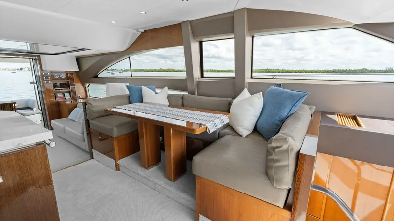 Slide: The Image of Spacious Salon with Dining Area The salon of the Princess 64 Flybridge offers a welcoming dining area with plush, L-shaped seating and a stylish wooden table. Large windows provide panoramic views and natural light, enhancing the open and airy atmosphere. The modern design and comfortab - 7460820