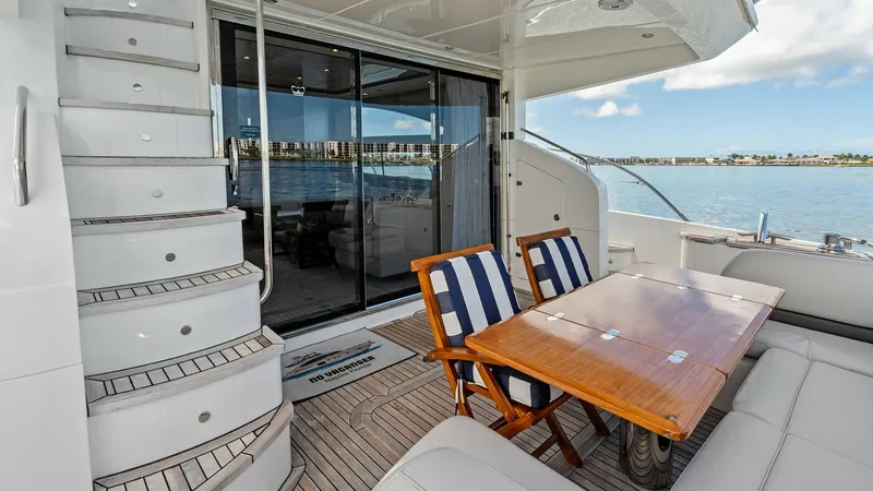 Slide: The Image of Aft Deck with Dining Area The aft deck of the 2016 Princess 64 Flybridge offers an inviting outdoor dining area with a sleek teak table and comfortable striped chairs. The elegant teak decking complements the modern design, while the sliding glass doors provide seamless access to - 7460808