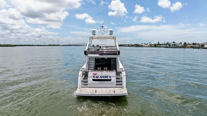 Slide: The Image of Aft View with Swim Platform This image showcases the aft view of the 2016 Princess 64 Flybridge yacht, 'No Vacansea.' The spacious swim platform offers easy access to the water, perfect for leisurely activities or docking. The sleek design and elegant lines of the stern highlight th - 7460803