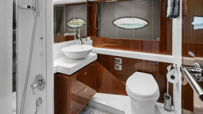 Slide: The Image of Luxurious Ensuite Bathroom This elegant ensuite bathroom on the Princess 64 Flybridge features a sleek, modern design with high-gloss wood finishes and a stylish vessel sink. The space is enhanced by a large window, providing natural light and a touch of nautical charm. A spacious - 7460840