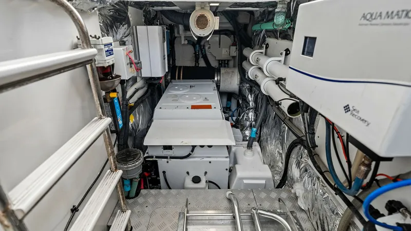Slide: The Image of Engine Room with Twin CAT C18 ACERT Engines This image showcases the well-organized engine room of the 2016 Princess 64 Flybridge. The space is equipped with high-quality machinery and systems, including the Aqua Matic water purification system, ensuring efficient operation and maintenance. The met - 7460880