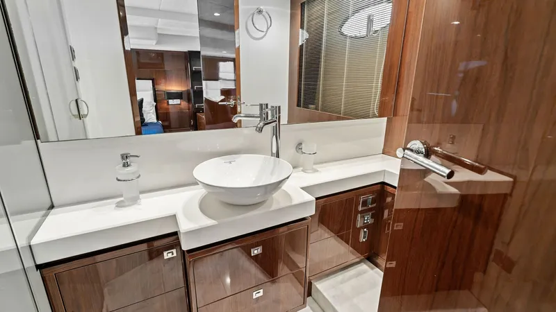 Slide: The Image of Elegant Master Bathroom Vanity Area This guest bathroom on the Princess 64 Flybridge features a stylish vanity with a modern vessel sink and sleek chrome fixtures. The rich wood cabinetry provides ample storage, while the high-gloss finish adds a touch of luxury. Soft overhead lighting and - 7460828