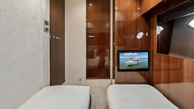 Slide: The Image of Twin Guest Stateroom with TV This elegant twin guest stateroom on the Princess 64 Flybridge features sleek wood paneling and plush twin beds, offering comfort and style. A wall-mounted TV provides entertainment, while the room's soft ambient lighting enhances its warm atmosphere. The - 7460845