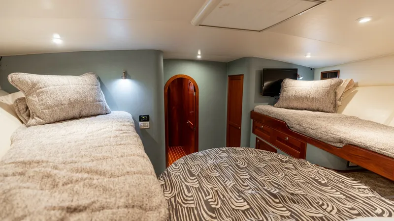 Slide: The Image of Guest Cabin with Twin Berths This inviting guest cabin on the 2006 Blackwell 65 Convertible features twin berths adorned with plush bedding, providing a cozy retreat. The warm wood finishes and subtle lighting create an elegant ambiance, while ample storage spaces ensure practicality - 7469762