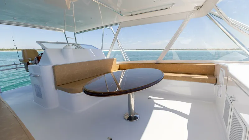 Slide: The Image of Flybridge Seating Area with Table The flybridge of the 2006 Blackwell 65 Convertible features a spacious seating area with a stylish, glossy wooden table, perfect for socializing while enjoying panoramic ocean views. The seating is upholstered in a warm, neutral tone, complementing the br - 7469775